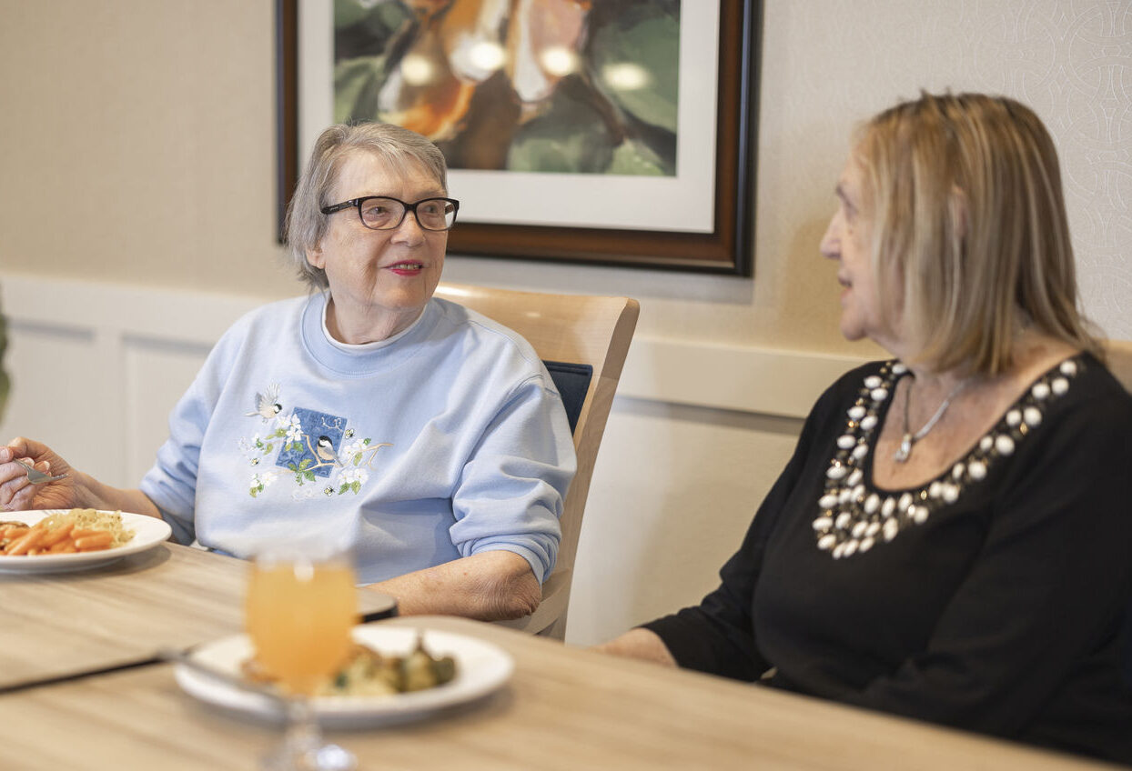 Residents enjoying a meal and conversation in a dining area