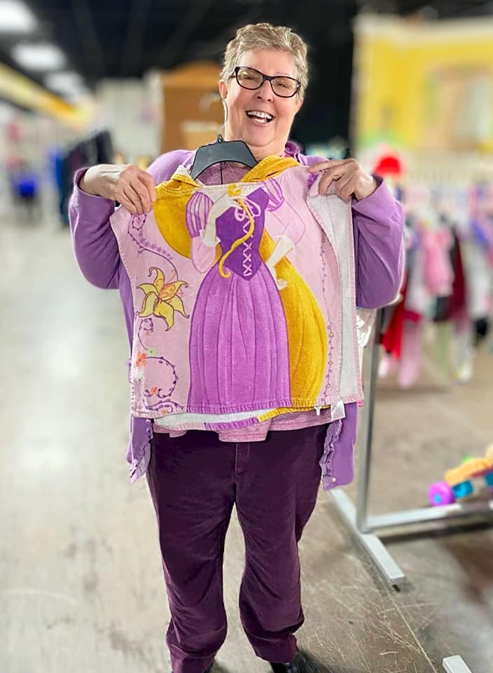Resident holding a colorful sweater in a cheerful interior space