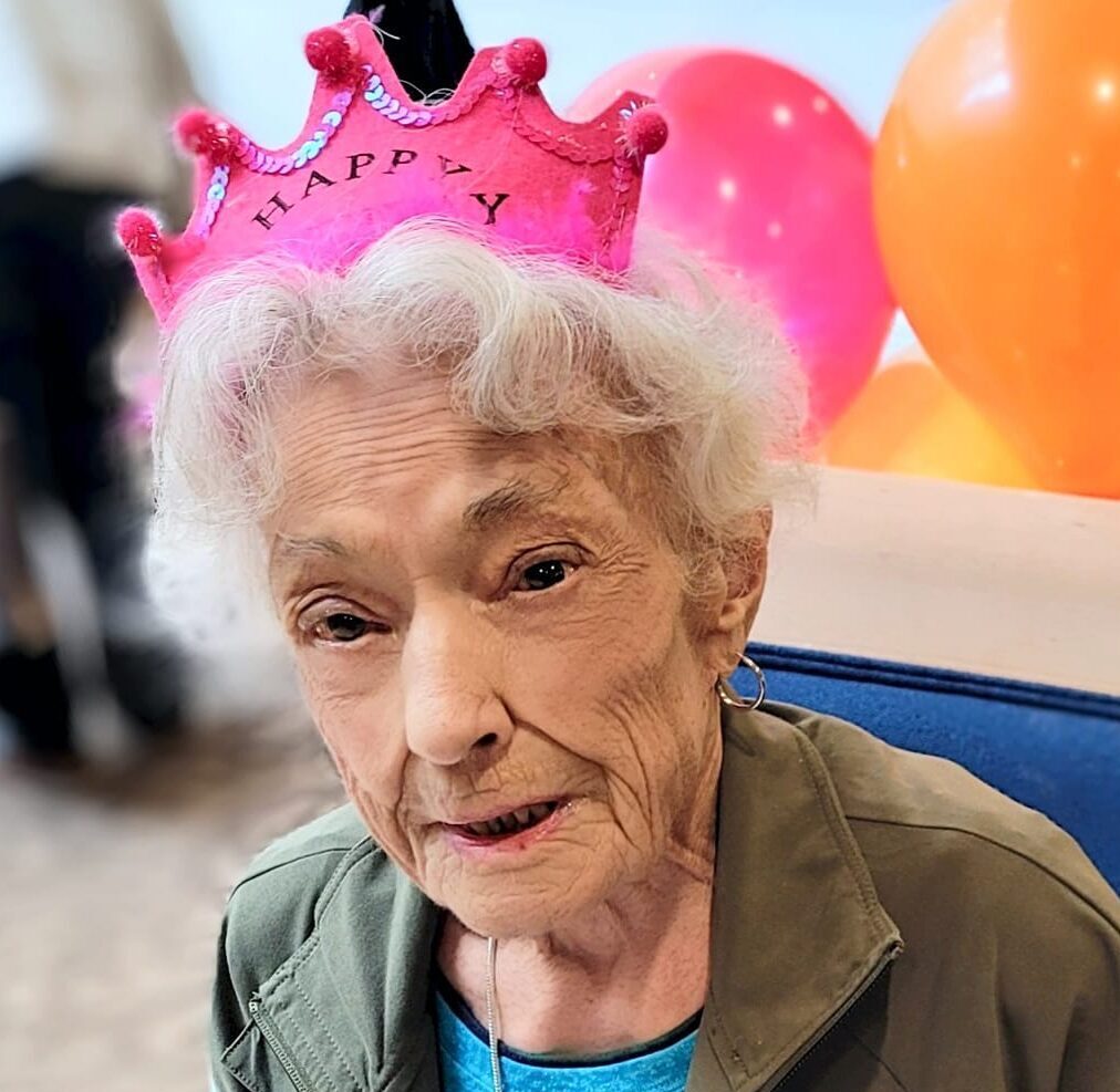 Elderly woman wearing a festive crown, smiling