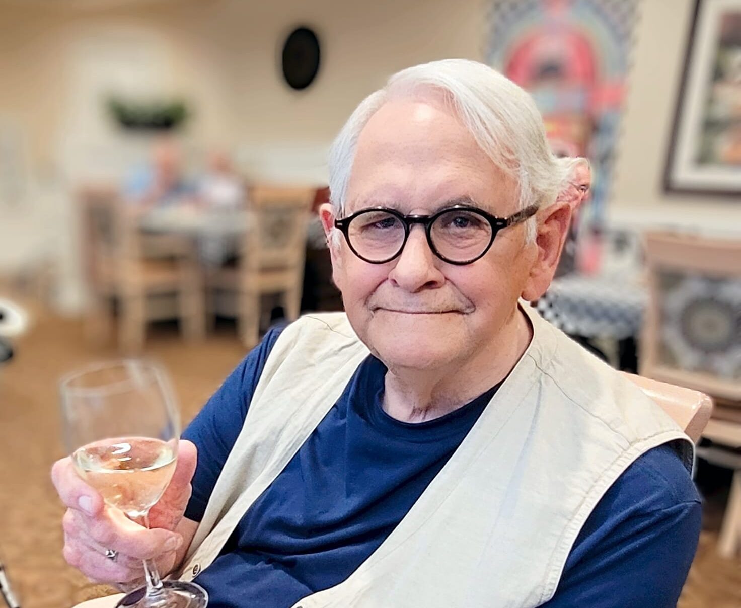 A smiling resident holding a glass of wine in a social area
