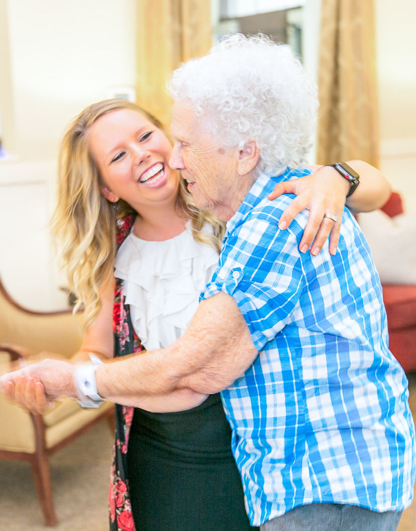 A resident enjoying a dance with staff in a common area