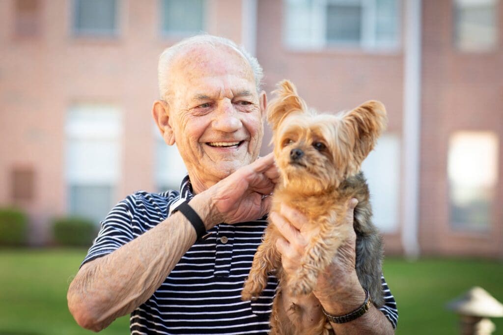 Senior man smiling with his dog outdoors