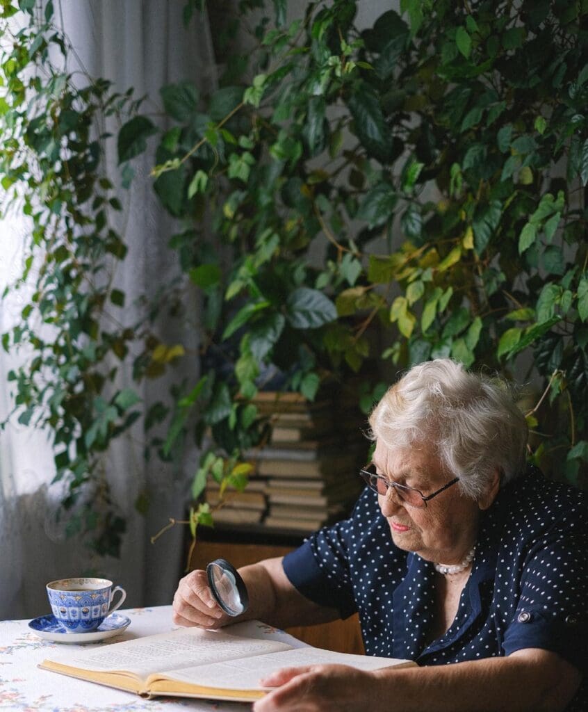 An elderly woman reading a book by a window