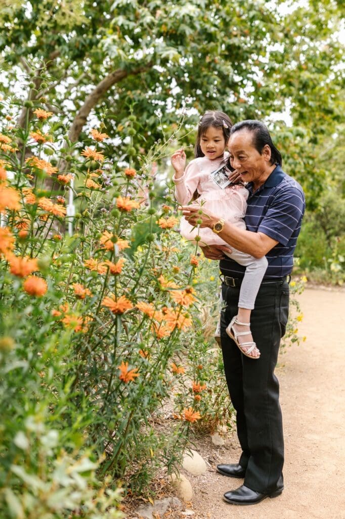 A man and girl interacting near vibrant flowers in a garden