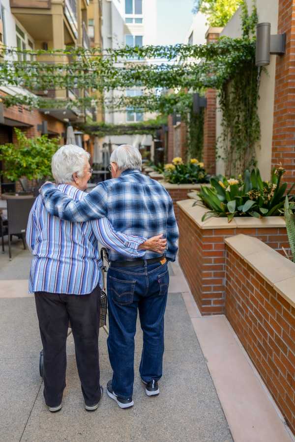Elderly couple walking together in a garden path