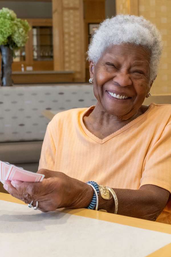 A senior woman smiling while playing cards indoors
