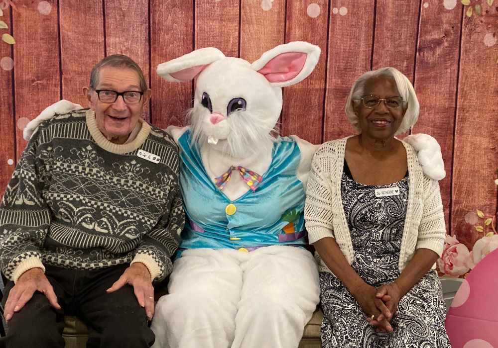 Two residents posing with the Easter Bunny in a festive setting.