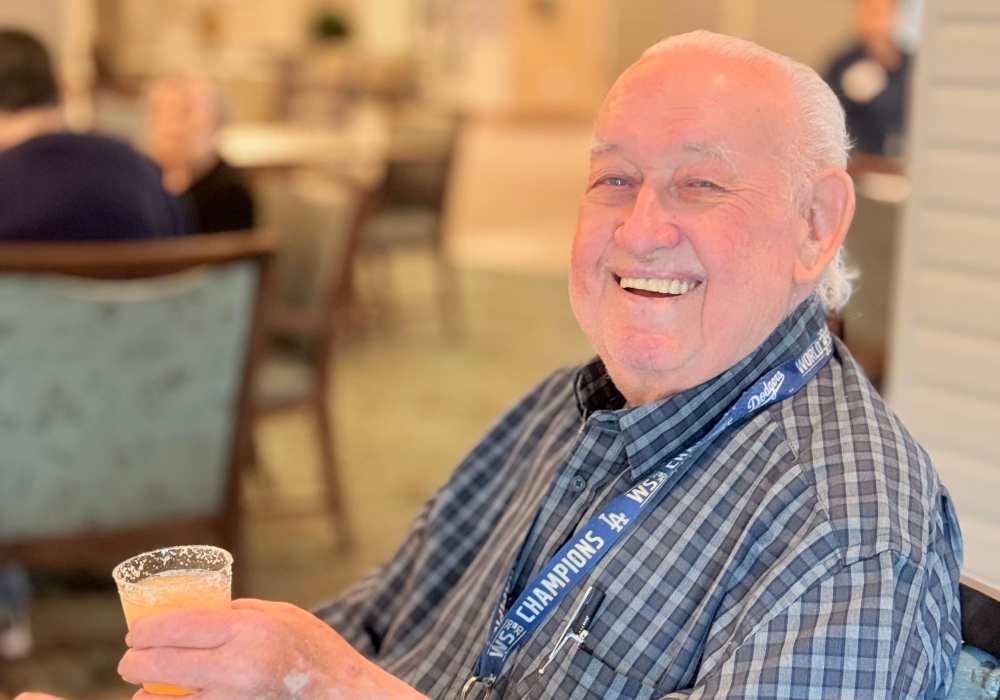 A smiling resident holding a drink in a common area