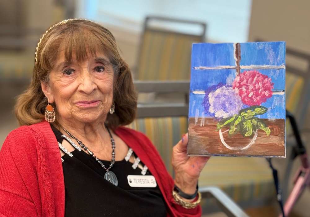 Resident showing her painting in an activity room