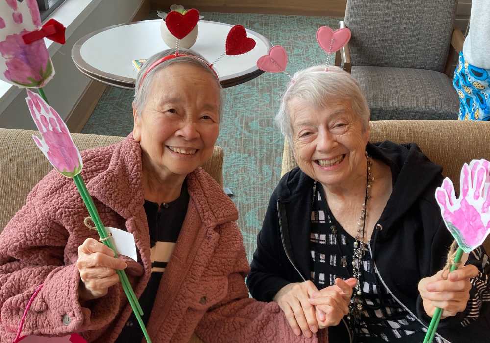 Two residents smiling and holding decorated flower stems