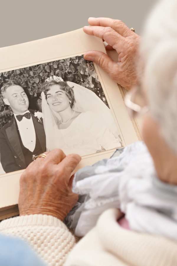 An elderly woman looking at a wedding photo