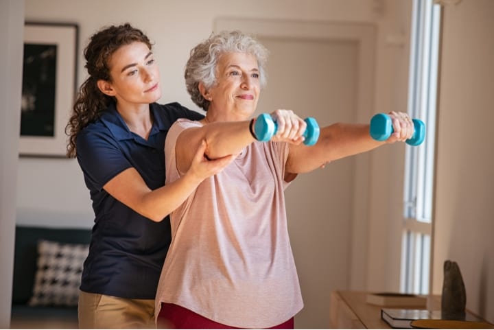 Senior resident exercising with staff assistance