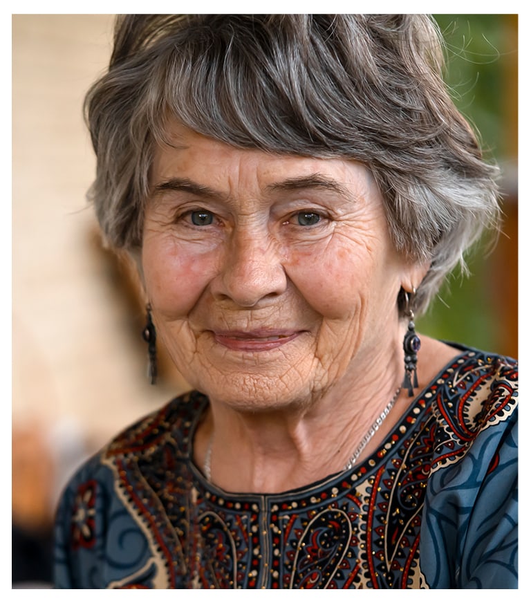 A smiling senior woman with gray hair and colorful attire
