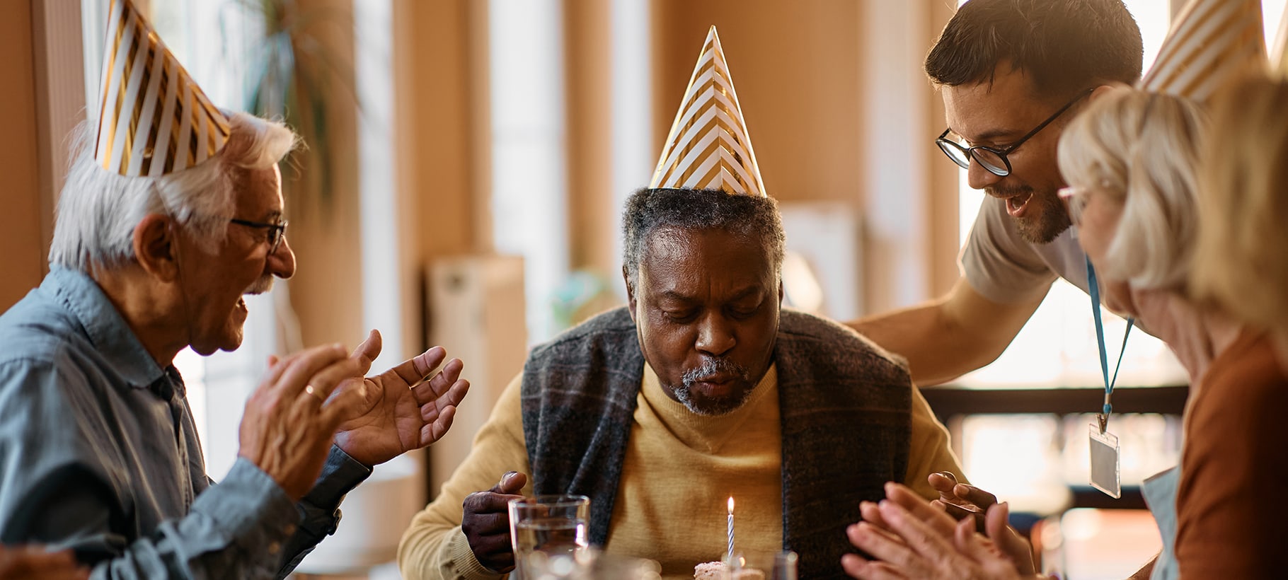 Residents celebrating a birthday with cake and hats