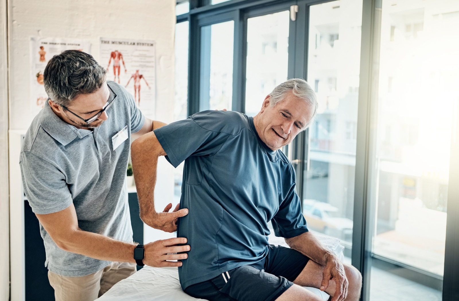 A therapist assisting an elderly man with mobility therapy.