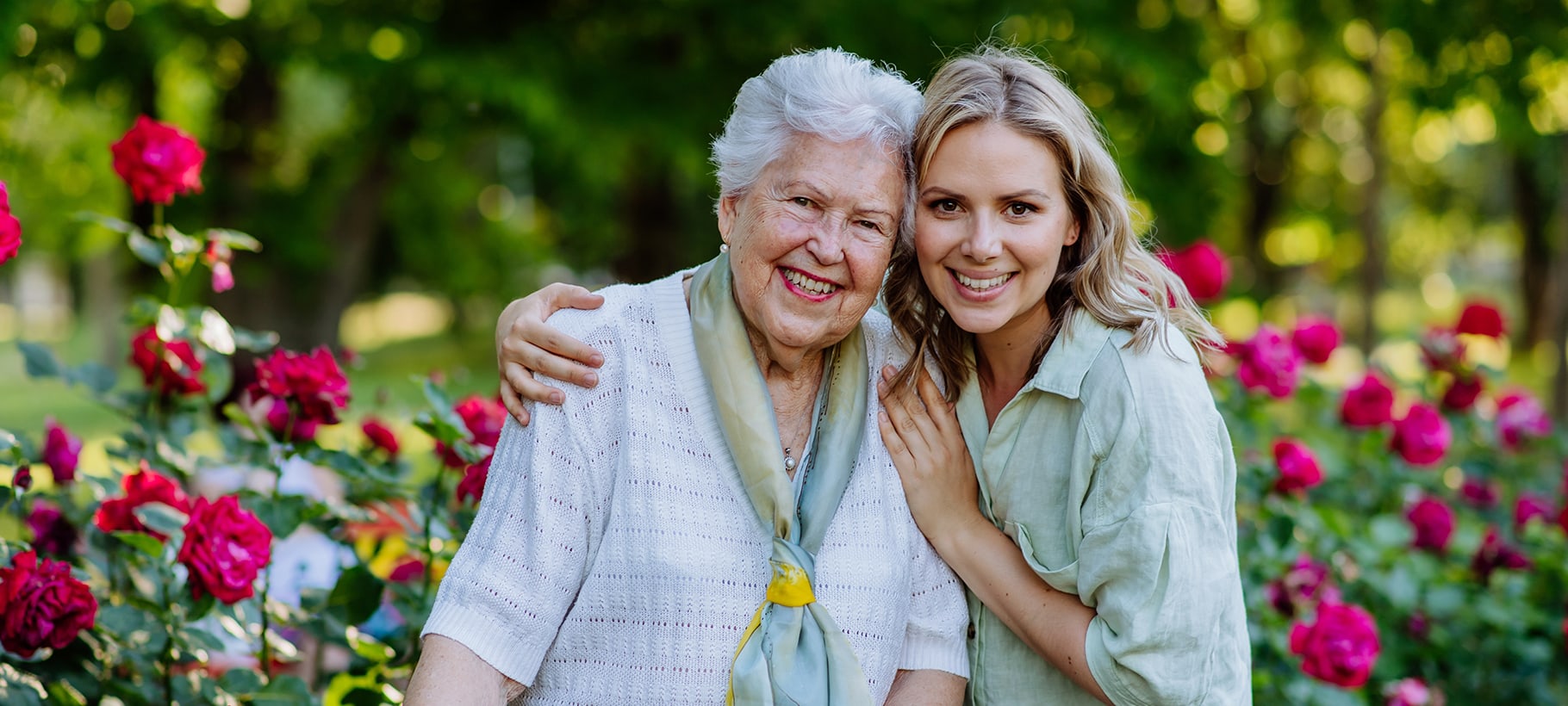 Smiling resident and staff member in a rose garden