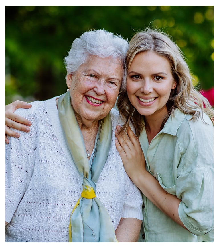 A smiling resident and staff member outdoors