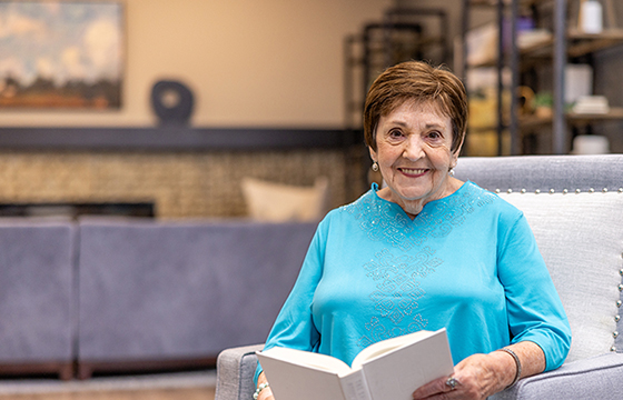 A cheerful resident reading a book in a cozy common area