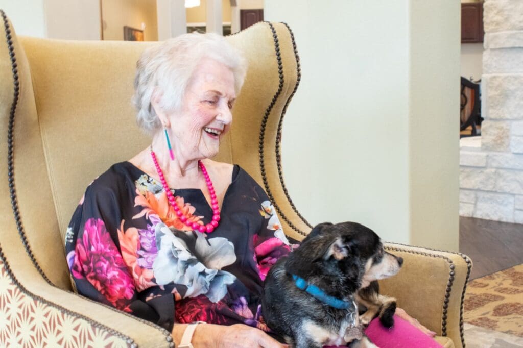 A happy resident enjoying time with a small dog in a cozy chair
