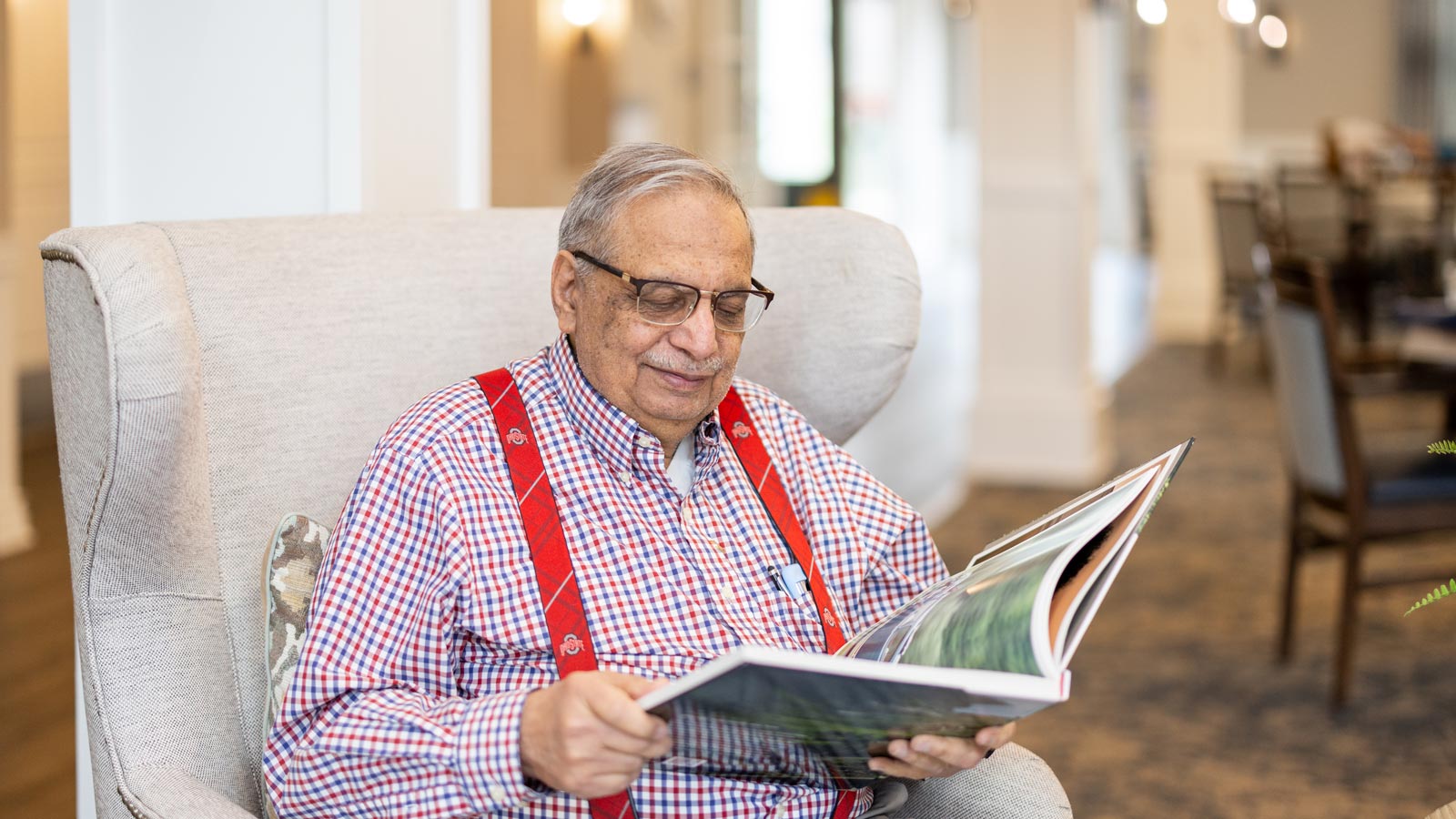 An older man reading a book in a cozy chair