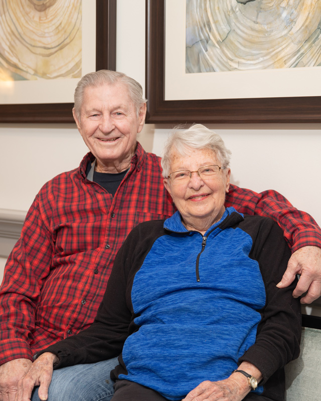 A smiling elderly couple sitting together indoors