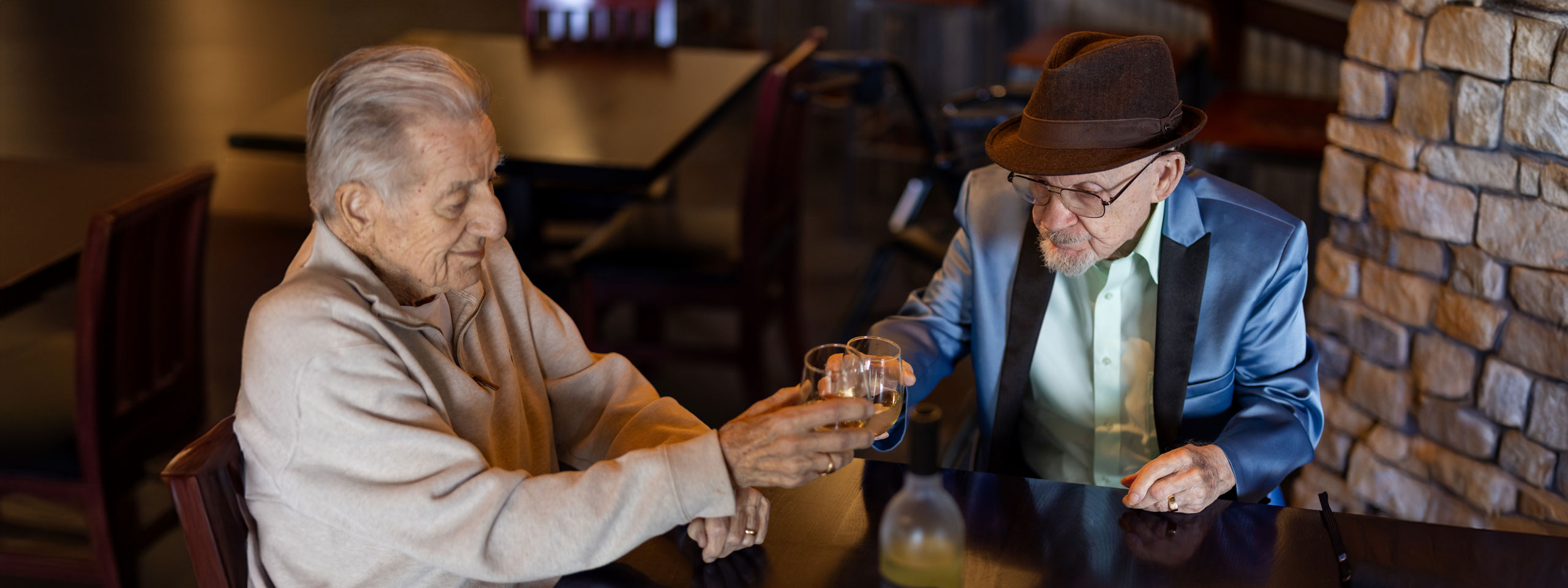 Two residents toasting drinks in a cozy setting