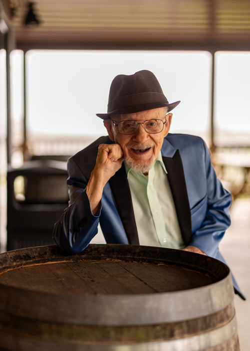 Elderly man smiling and posing with a barrel