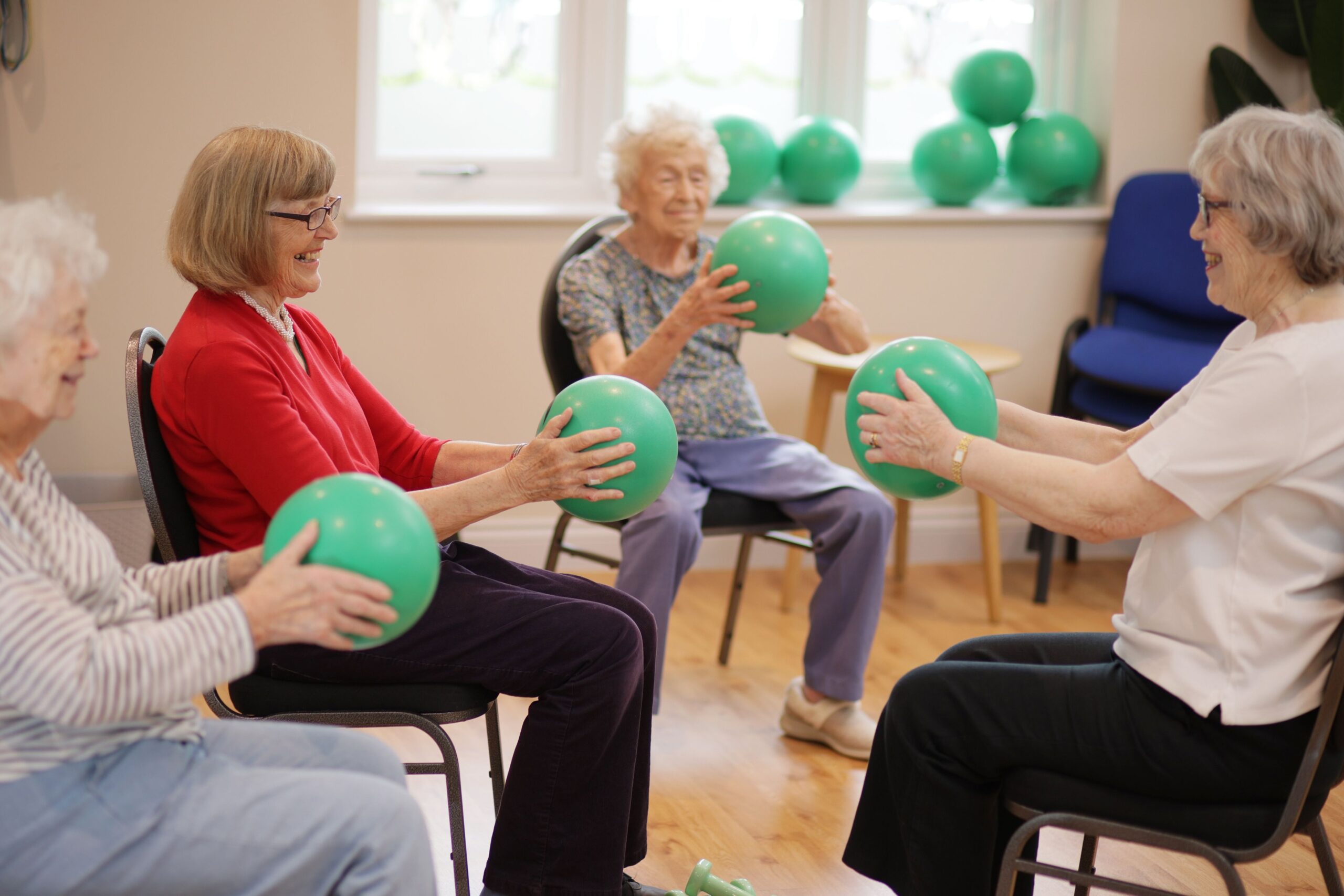 Residents participating in a seated exercise class with green balls