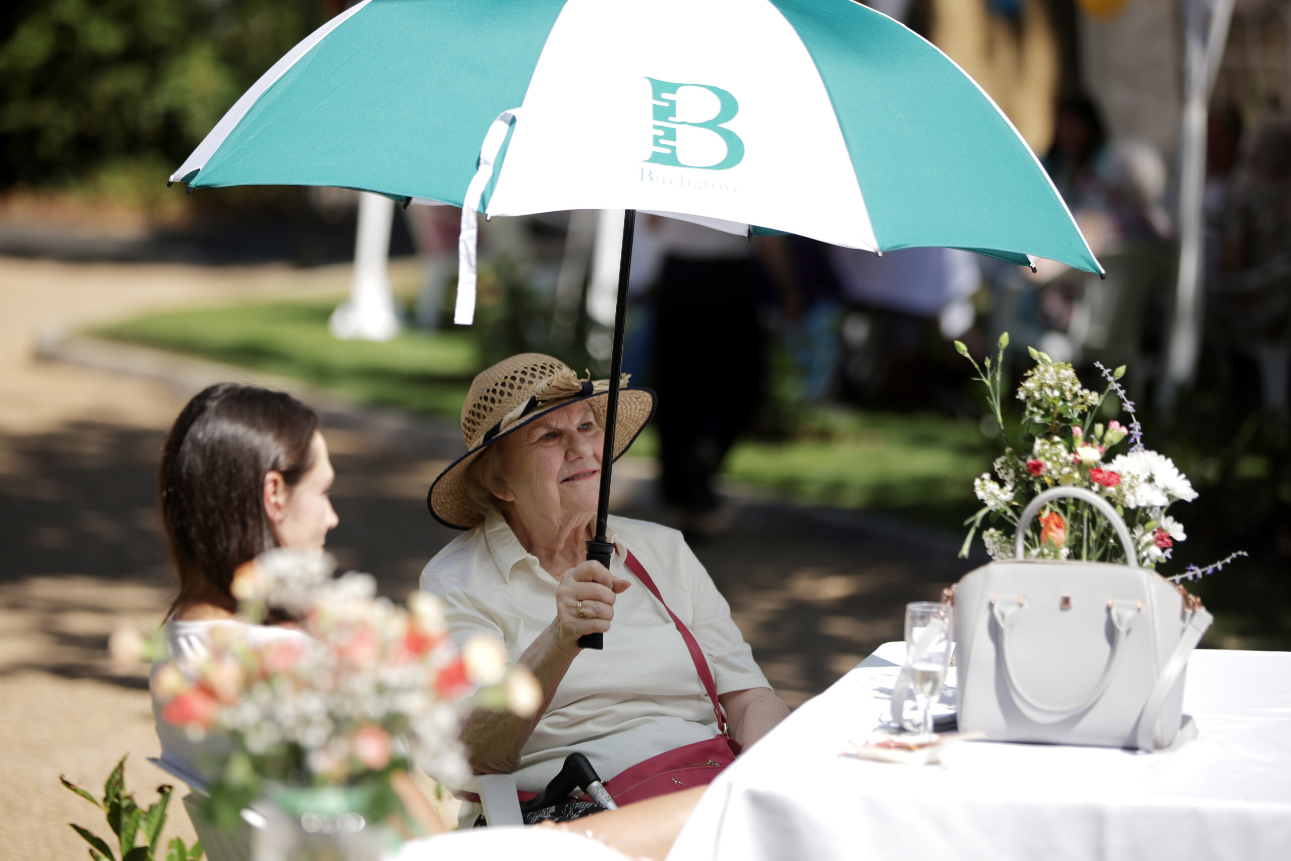 Residents enjoying a sunny outdoor gathering under umbrellas