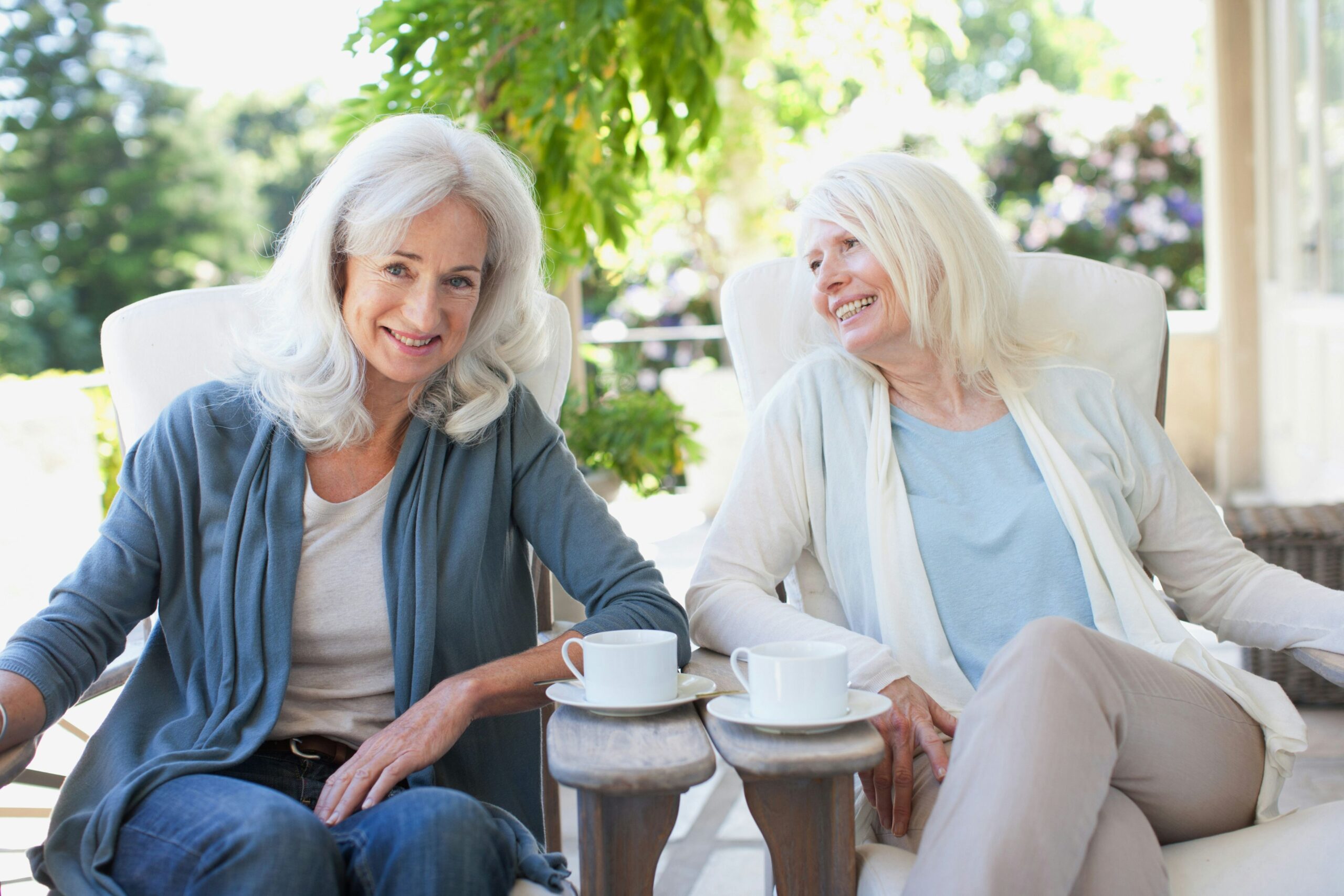 Two elderly women enjoying tea on a patio