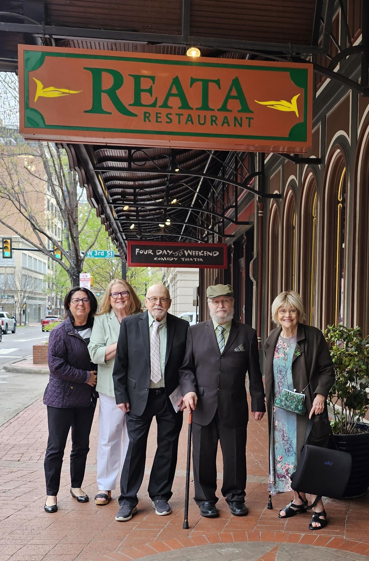 Guests posing outside a restaurant with a sign