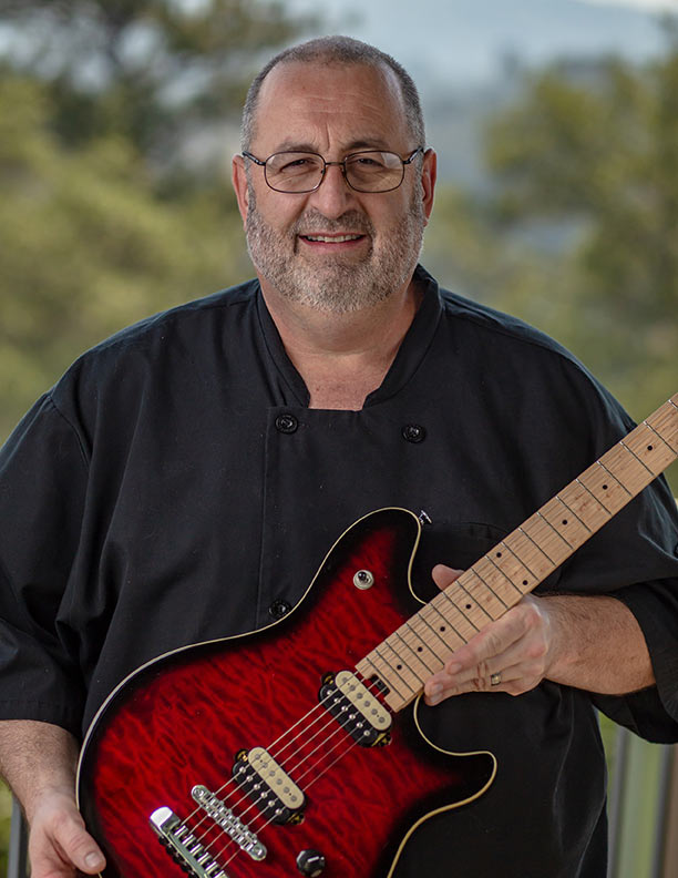Chef holding a guitar outdoors