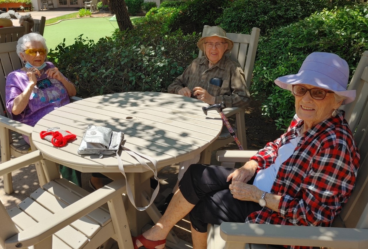 Three residents enjoying time outdoors at a table