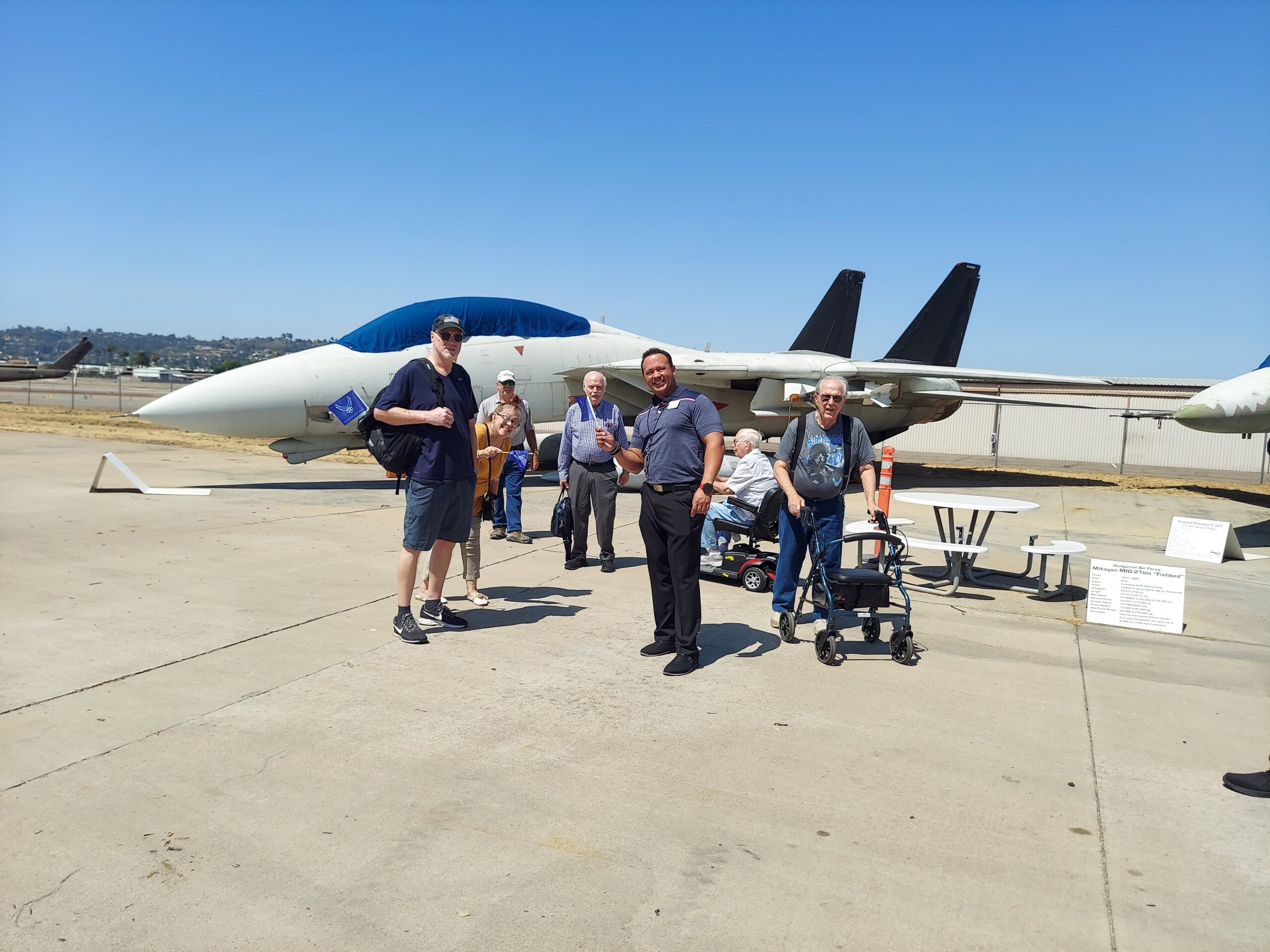 Residents and staff near a fighter jet in an outdoor area