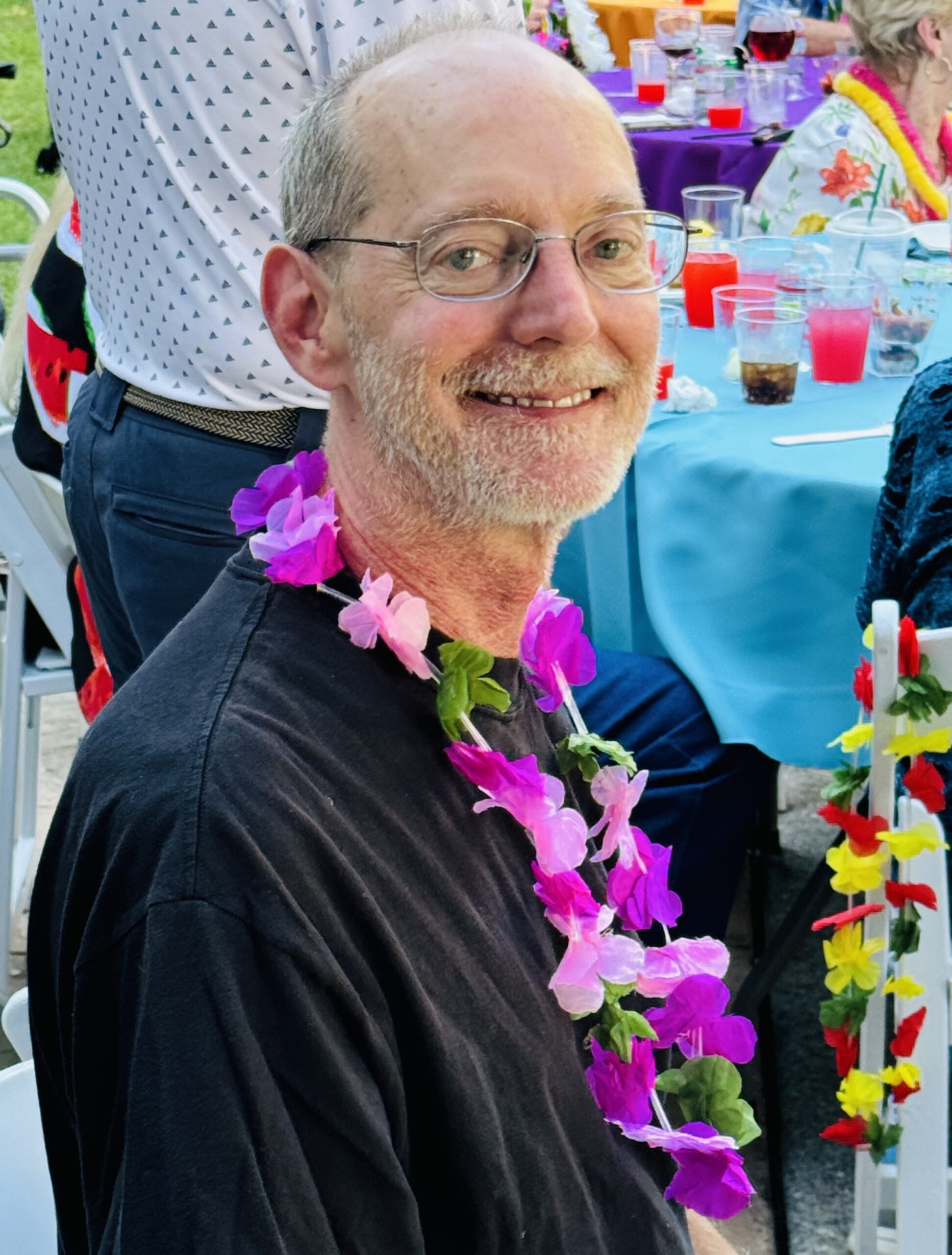 Resident smiling at a festive gathering wearing a floral lei