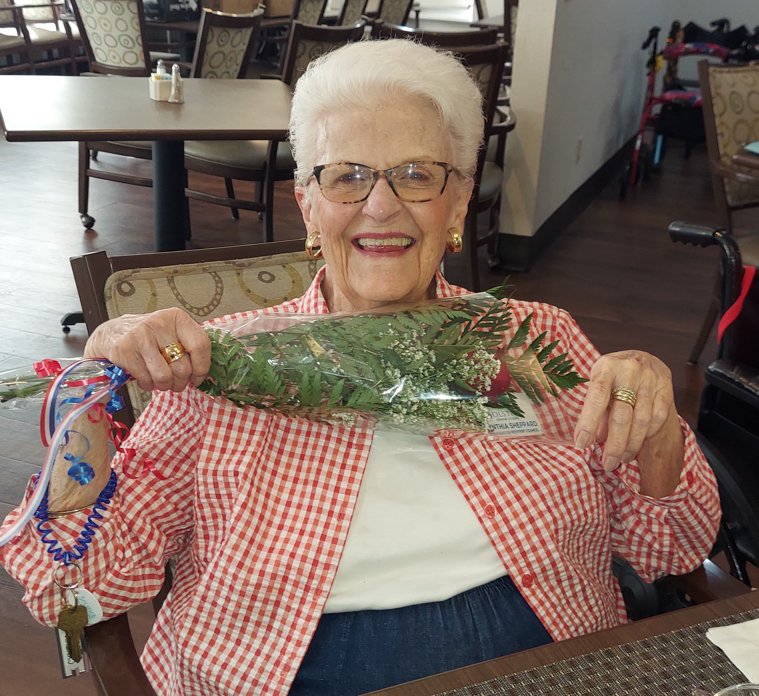 Resident smiling and holding decorative greenery in a communal area
