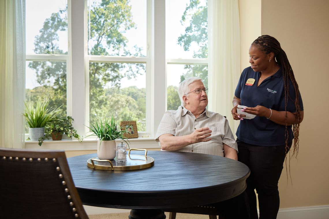 A caregiver chatting with an elderly resident in a bright room