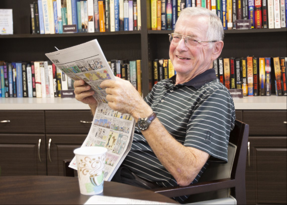Senior resident reading a newspaper in a bright room