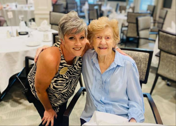 A staff member with a resident smiling in a dining area