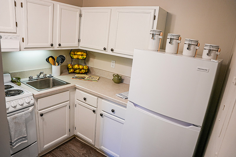 A bright kitchen interior with white cabinets and appliances