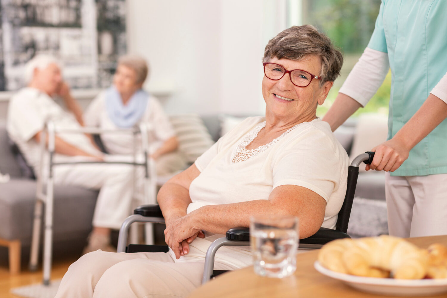 A smiling resident in a wheelchair with staff in the background