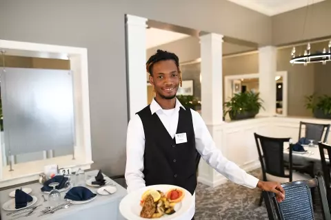 Staff member serving food in the dining room