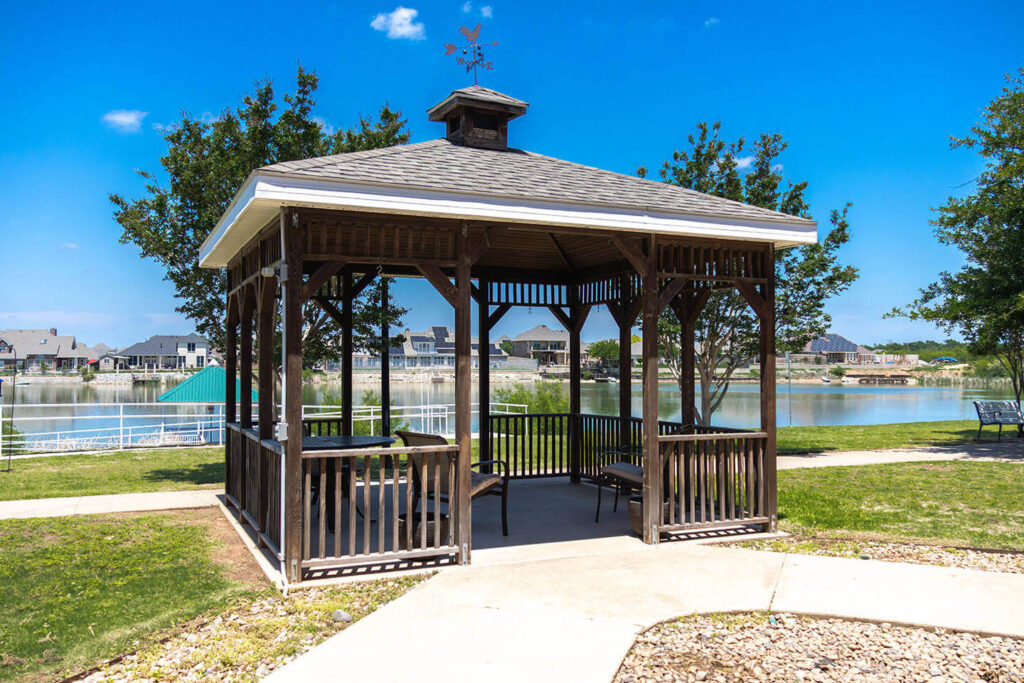 Outdoor gazebo by the lake in a park-like setting.