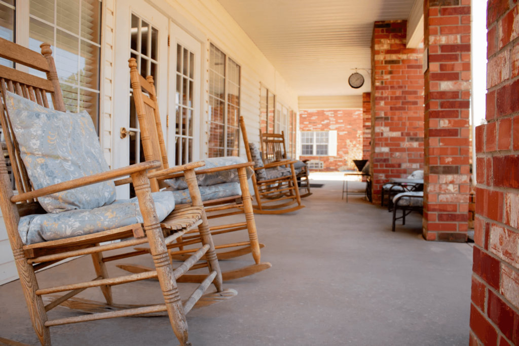 Rocking chairs on a porch outside a building.