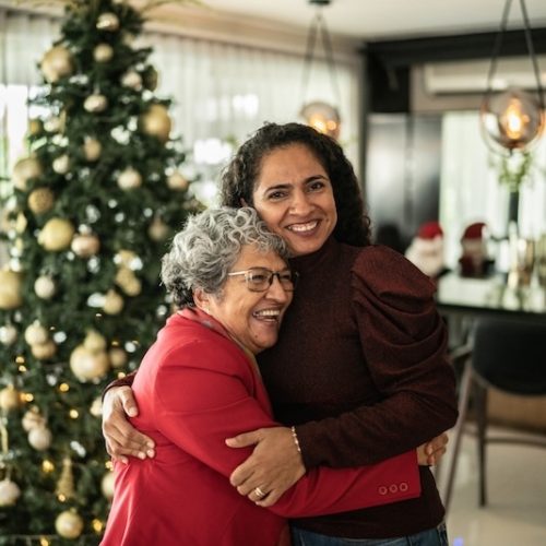 Two women embracing in a festive interior space.