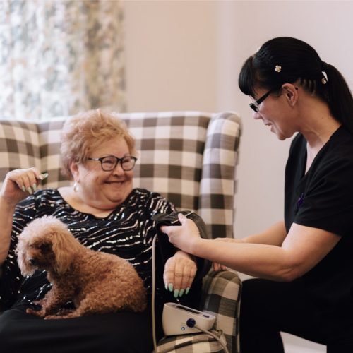 Smiling resident with caregiver and dog
