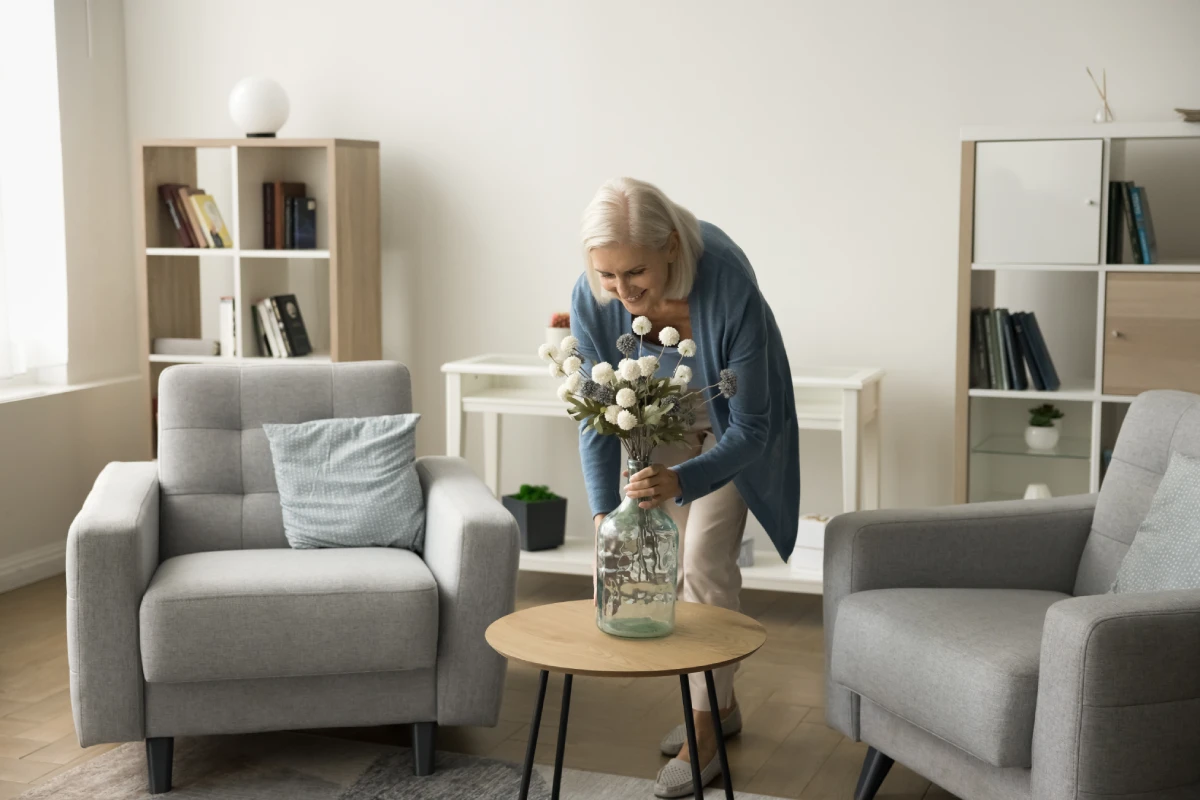 Resident arranging flowers in a cozy common area.