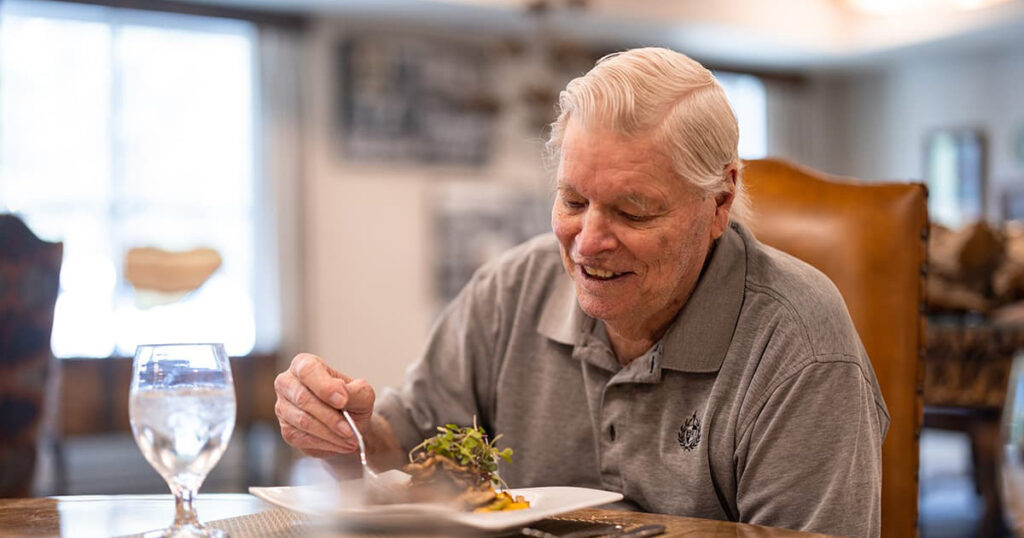 Elderly man enjoying a meal in dining area.
