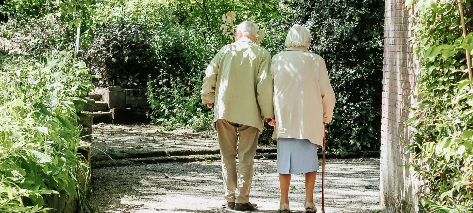Elderly couple walking in a garden pathway