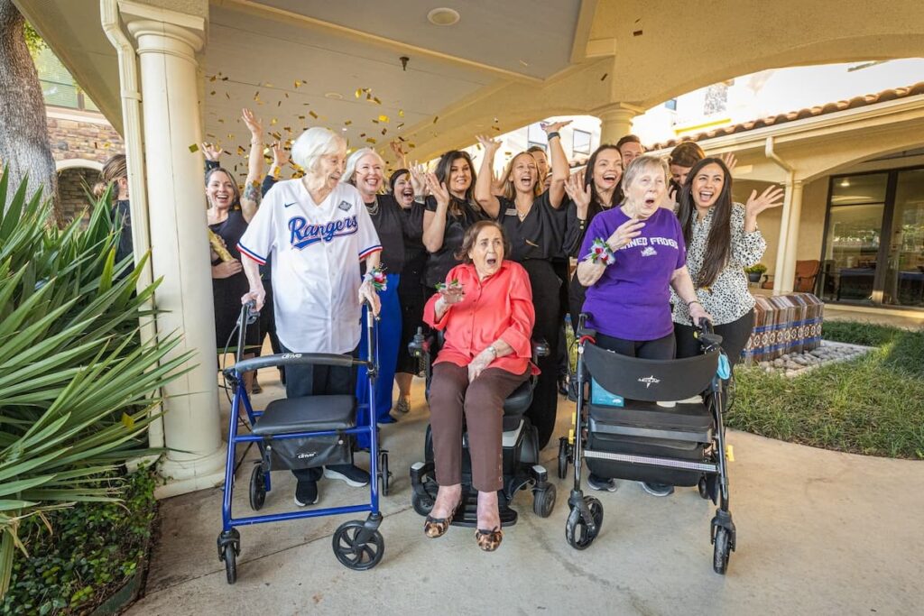 Residents and staff celebrating outdoors with joy.